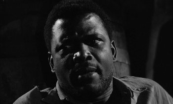 Movie still from “The Defiant Ones” (1958), directed by Stanley Kramer – A black and white photo of a man with a serious look on his face; Close Up shot, Low angle