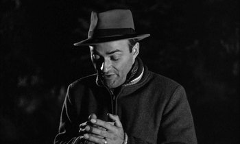 Movie still from “The Defiant Ones” (1958), directed by Stanley Kramer – A black and white photo of a man wearing a hat and looking down at his cell phone; Close Up shot, Low angle