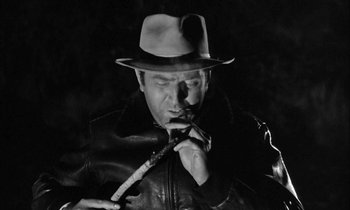 Movie still from “The Defiant Ones” (1958), directed by Stanley Kramer – A black and white photo of a man smoking a pipe; Close Up shot, High angle