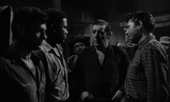 Movie still from “The Defiant Ones” (1958), directed by Stanley Kramer – A group of men standing next to each other in a room; Medium shot, Over the shoulder angle