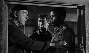 Movie still from “The Defiant Ones” (1958), directed by Stanley Kramer – A group of men standing next to each other in a room; Medium shot, Over the shoulder angle