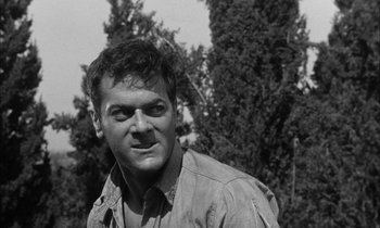 Movie still from “The Defiant Ones” (1958), directed by Stanley Kramer – Black and white photograph of a man in front of trees; Close Up shot, Low angle