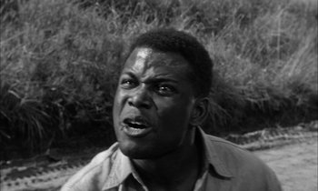 Movie still from “The Defiant Ones” (1958), directed by Stanley Kramer – A black and white photo of a man in a field; Close Up shot, Low angle