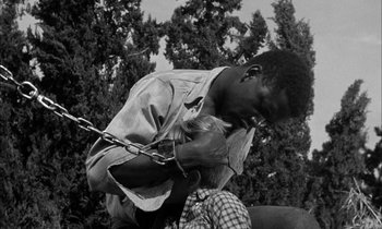 Movie still from “The Defiant Ones” (1958), directed by Stanley Kramer – A black and white photo of a man holding a chain; Medium shot, High angle