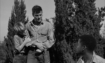 Movie still from “The Defiant Ones” (1958), directed by Stanley Kramer – A man and two children standing next to a tree; Medium shot, Over the shoulder angle