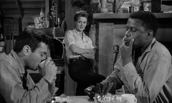 Movie still from “The Defiant Ones” (1958), directed by Stanley Kramer – A group of people sitting around a table; Medium shot, Over the shoulder angle