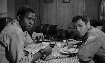 Movie still from “The Defiant Ones” (1958), directed by Stanley Kramer – Two men sitting at a table with a plate of food; Medium shot, Low angle