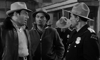Movie still from “The Defiant Ones” (1958), directed by Stanley Kramer – A group of men standing next to each other on a street; Medium shot, Over the shoulder angle