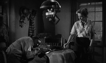 Movie still from “The Defiant Ones” (1958), directed by Stanley Kramer – A man and a woman are sitting at a dinner table; Medium shot, Low angle