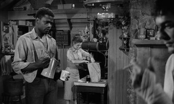 Movie still from “The Defiant Ones” (1958), directed by Stanley Kramer – A man and a woman standing next to each other in front of an oven; Medium shot, Low angle