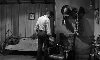Movie still from “The Defiant Ones” (1958), directed by Stanley Kramer – A black and white photo of a man in a room; Medium shot, High angle