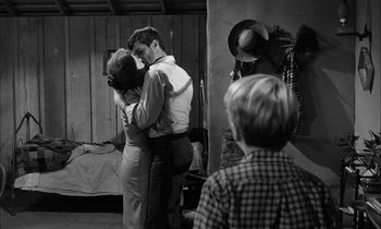 Movie still from “The Defiant Ones” (1958), directed by Stanley Kramer – A man and a woman hugging in a room with a young boy; Wide shot, Over the shoulder angle