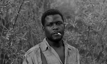 Movie still from “The Defiant Ones” (1958), directed by Stanley Kramer – A black and white photo of a man smoking a cigarette; Close Up shot, Low angle