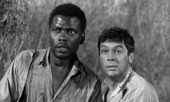 Movie still from “The Defiant Ones” (1958), directed by Stanley Kramer – A black and white photo of two men standing next to each other; Close Up shot, Low angle