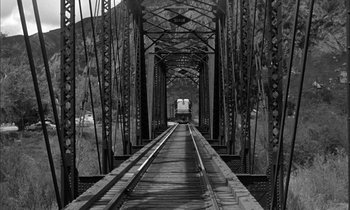 Movie still from “The Defiant Ones” (1958), directed by Stanley Kramer – A black and white photo of a train crossing a bridge; Extreme Wide shot, Low angle