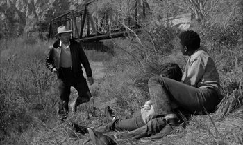 Movie still from “The Defiant Ones” (1958), directed by Stanley Kramer – A group of people sitting on the ground in the grass; Wide shot, High angle