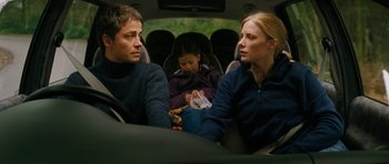 Movie still from “The Descent” (2005), directed by Neil Marshall – A man and a woman sit in a car with a little girl; Medium shot, Over the shoulder angle