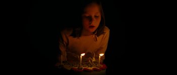 Movie still from “The Descent” (2005), directed by Neil Marshall – A little girl blowing out candles on a birthday cake; Extreme Close Up shot, High angle