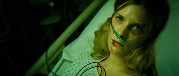 Movie still from “The Descent” (2005), directed by Neil Marshall – A woman with a face mask on laying in a hospital bed; Close Up shot, High angle