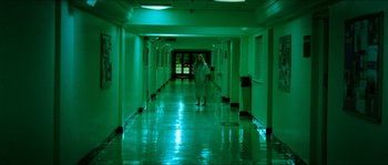 Movie still from “The Descent” (2005), directed by Neil Marshall – A person walking down a long hallway in a building; Wide shot, High angle