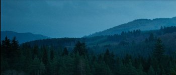 Movie still from “The Descent” (2005), directed by Neil Marshall – A view of a forest at night with a cloudy sky; Extreme Wide shot, Low angle