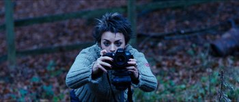 Movie still from “The Descent” (2005), directed by Neil Marshall – A woman taking a picture with a camera; Medium shot, Low angle
