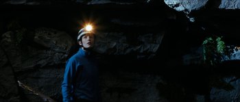 Movie still from “The Descent” (2005), directed by Neil Marshall – A man with a headlamp in a cave; Medium shot, Low angle