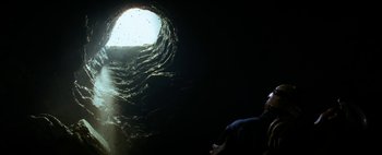 Movie still from “The Descent” (2005), directed by Neil Marshall – A man standing in front of a hole in the ground; Extreme Wide shot, High angle