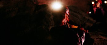 Movie still from “The Descent” (2005), directed by Neil Marshall – A person with a headlamp in a cave; Close Up shot, Low angle