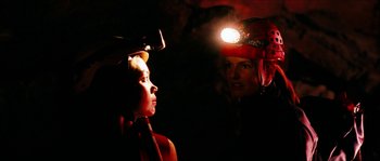 Movie still from “The Descent” (2005), directed by Neil Marshall – Two people in a cave with a head lamp on; Close Up shot, Over the shoulder angle