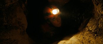 Movie still from “The Descent” (2005), directed by Neil Marshall – A person with a headlamp in the dark; Medium shot, Low angle