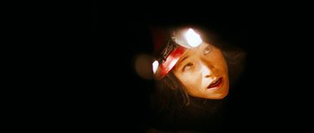 Movie still from “The Descent” (2005), directed by Neil Marshall – A woman wearing a headlamp looking into the camera; Close Up shot, Low angle