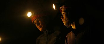 Movie still from “The Descent” (2005), directed by Neil Marshall – Two people are standing in the dark with headlamps on; Medium shot, Low angle