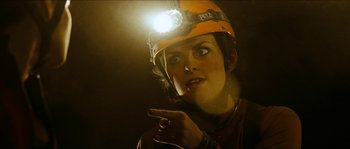 Movie still from “The Descent” (2005), directed by Neil Marshall – A woman wearing a hard hat pointing to her face; Close Up shot, Low angle