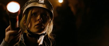Movie still from “The Descent” (2005), directed by Neil Marshall – A woman wearing a hard hat in the dark; Close Up shot, Low angle