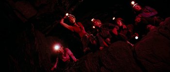 Movie still from “The Descent” (2005), directed by Neil Marshall – A group of people climbing up a rock wall at night with headlamps on; Wide shot, Low angle