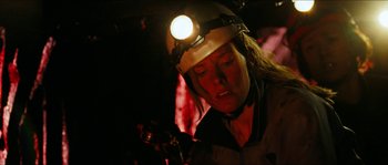 Movie still from “The Descent” (2005), directed by Neil Marshall – A woman wearing a hard hat with a light on her head; Close Up shot, Overhead angle