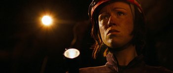 Movie still from “The Descent” (2005), directed by Neil Marshall – A person with a helmet on holding a flashlight in the dark; Close Up shot, Low angle