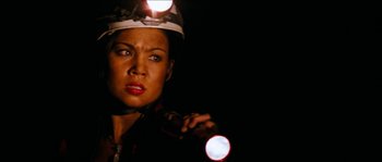 Movie still from “The Descent” (2005), directed by Neil Marshall – A woman holding a flashlight in a dark room; Close Up shot, High angle