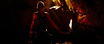 Movie still from “The Descent” (2005), directed by Neil Marshall – A person holding a fire in a cave; Medium shot, High angle