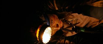 Movie still from “The Descent” (2005), directed by Neil Marshall – A person with a light in their face; Close Up shot, Overhead angle
