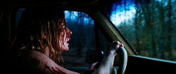 Movie still from “The Descent” (2005), directed by Neil Marshall – A woman with blood all over her face driving a car; Close Up shot, Over the shoulder angle