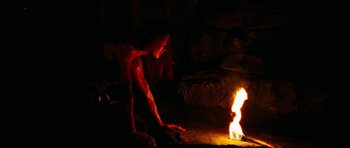 Movie still from “The Descent” (2005), directed by Neil Marshall – A woman sitting on the ground next to a fire; Medium shot, High angle