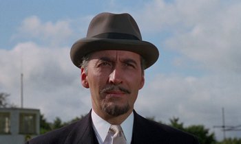 Movie still from “The Devil Rides Out” (1968), directed by Terence Fisher – A person wearing a suit and a hat; Close Up shot, Low angle
