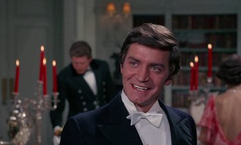Movie still from “The Devil Rides Out” (1968), directed by Terence Fisher – A person wearing a suit and bow tie; Close Up shot, Over the shoulder angle