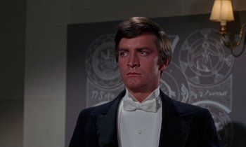 Movie still from “The Devil Rides Out” (1968), directed by Terence Fisher – A person wearing a suit and bow tie; Close Up shot, Low angle