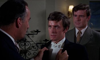 Movie still from “The Devil Rides Out” (1968), directed by Terence Fisher – A man in a suit and bow tie looking at his reflection in a mirror; Close Up shot, Over the shoulder angle