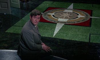 Movie still from “The Devil Rides Out” (1968), directed by Terence Fisher – A man sitting in front of a floor with an image on it; Medium shot, High angle