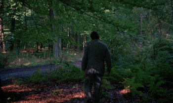 Movie still from “The Devil Rides Out” (1968), directed by Terence Fisher – A man walking through the woods in the evening; Extreme Wide shot, High angle