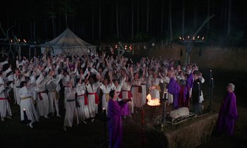 Movie still from “The Devil Rides Out” (1968), directed by Terence Fisher – A large group of people standing in front of a fire; Extreme Wide shot, High angle